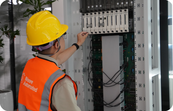 Moore Automated technician reviewing modules in an industrial control cabinet